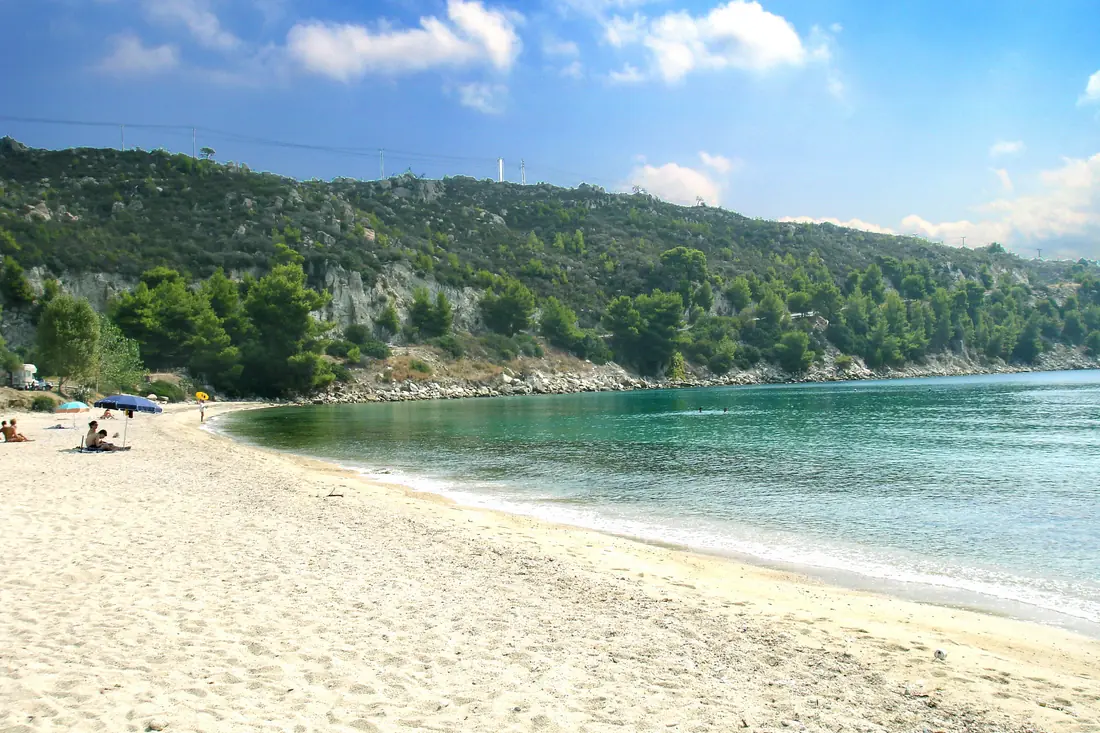 Sandy bay at Agios Ioannis near Nikiti with pale sand, gently shelving water and a wooded slope