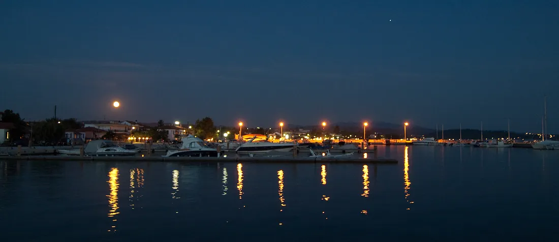 Nikiti at night seen from the water, the lights of the promenade reflected in the sea