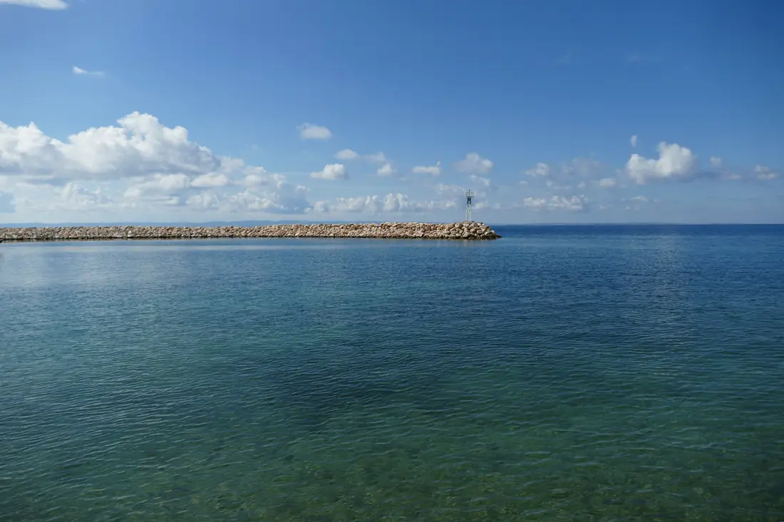 The breakwater at the entrance to Nikiti harbour with its beacon, the calm Toroneos gulf beyond