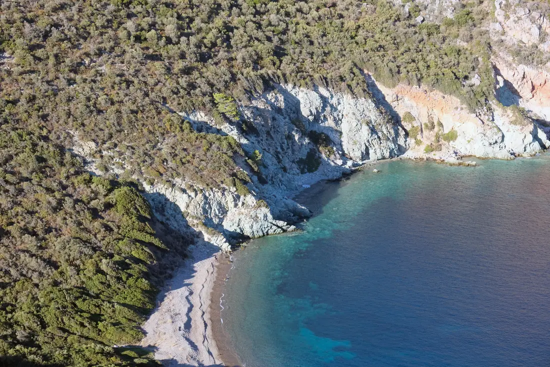 The long sandy beach at Toroni with clear shallow water and wooded hills behind