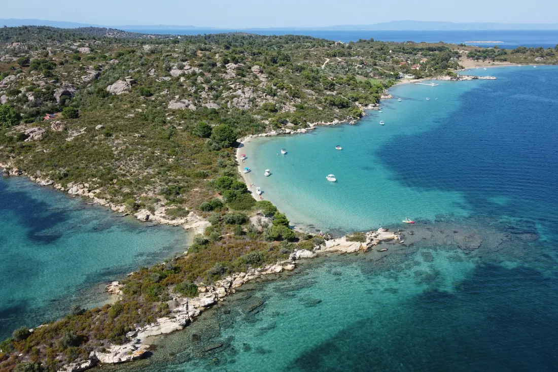 Aerial view of a bay off Vourvourou, turquoise shallows between wooded headlands